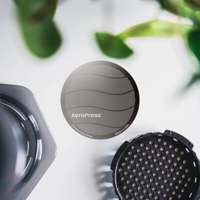 Billede af en metalfilter i centrum og en skilt Aeropress i kanten.