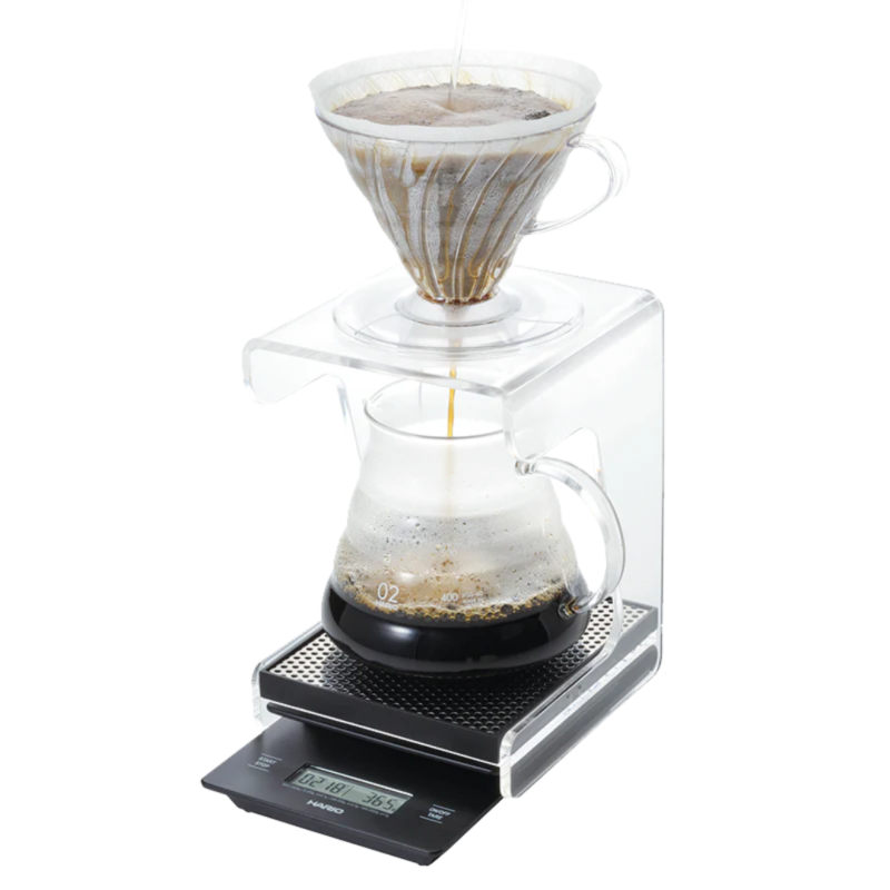 V60-Drip-station med en vægt under, en range server ovenpå risten og en v60 plastik dripper på toppen. I Dripperen er der kaffe og vand som løber ned i range serven.