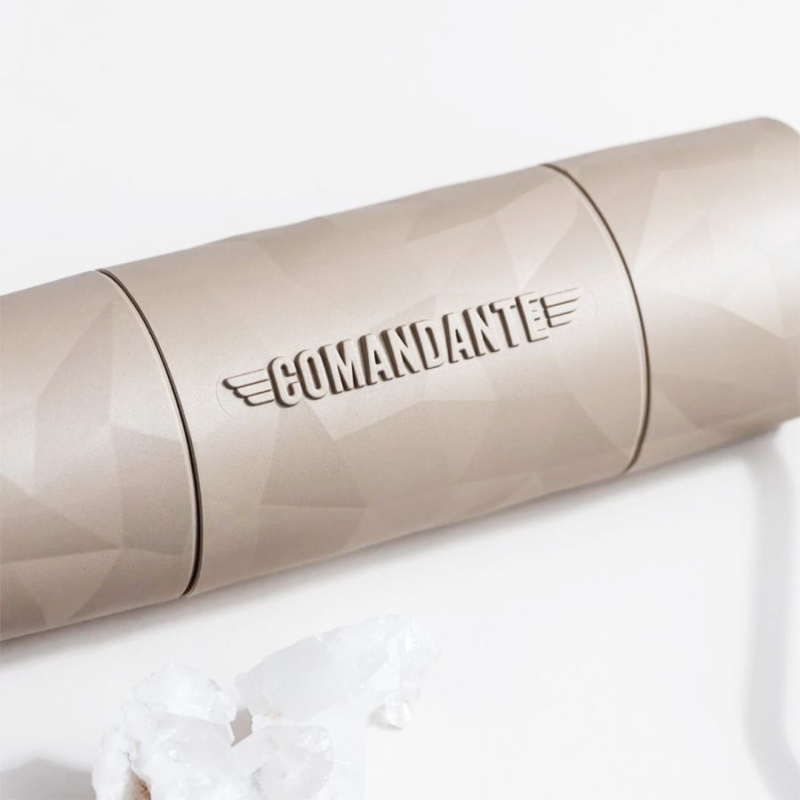 Nærbillede af Comandante X25 kaffekværn, liggende ned og viser den detaljerede, facetterede overflade og det indgraverede "Comandante"-logo på kværnens krop.