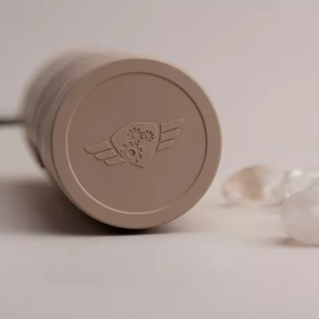 Bunden af Comandante X25 kaffekværn med fokus på logoet, der er præget i plasten og viser tandhjulsmotivet med vinger, som er en del af brandets ikonografi.