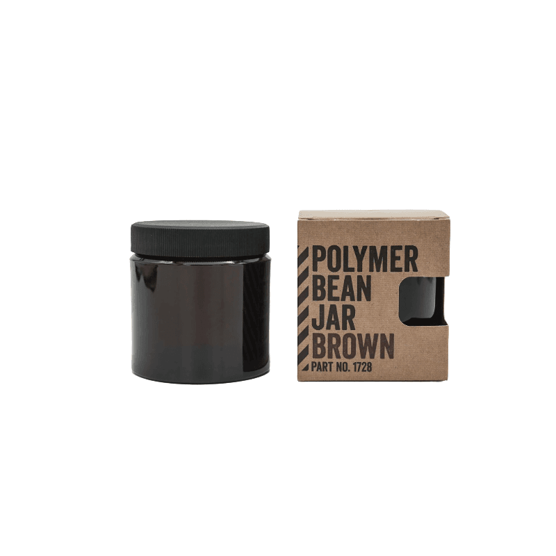 Comandante bønnebeholder i brun med sort låg. Til højre står beholderen i dens emballage med skriften "Polymer Bean Jar Brown"
