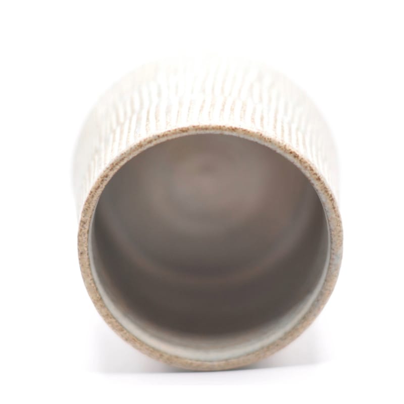 Indersiden af en blå keramikkop med smalle riller, afslører den glaserede overflade.