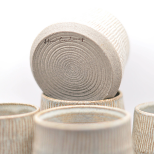 En samling af håndlavede blå keramikkopper med rillede mønstre, stablet sammen.