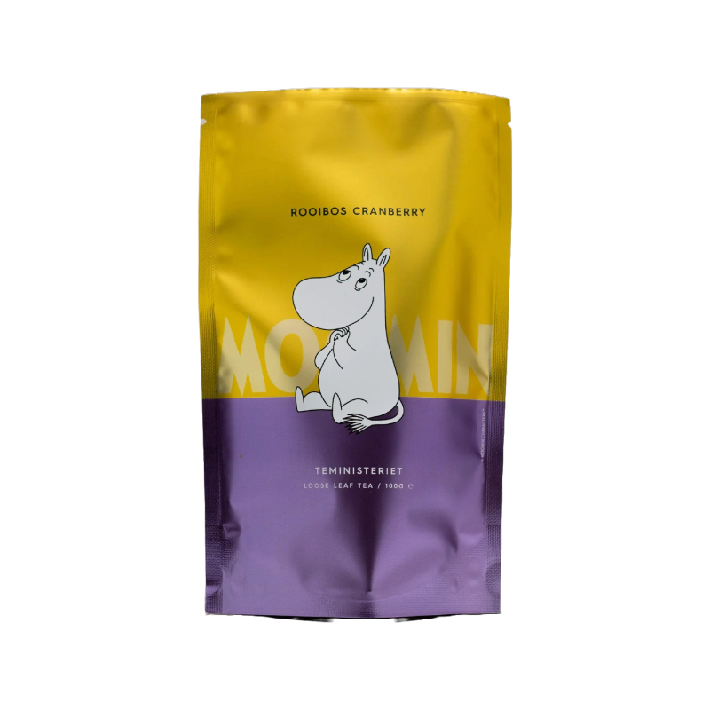 Teministeriet Moomin Rooibos Cranberry te i en farverig ståpose med gult øverst og lilla nederst. På forsiden er en illustration af Mummitrolden, der sidder med et roligt udtryk. Produktnavnet "Rooibos Cranberry" er trykt øverst, mens "Moomin" står bag figuren i en stor, tonet skrift. Nederst står "Teministeriet Loose Leaf Tea / 100 g" i hvid skrift. Baggrunden er neutral, og posen har en let reflekterende overflade.