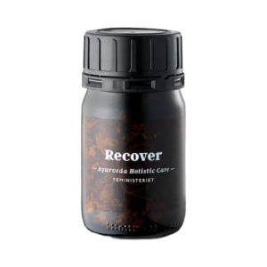 Teministeriet Ayurveda Recover Te i en elegant sort beholder med gennemsigtigt materiale, der viser de naturlige ingredienser som lakridsrod, kanel og ingefær. En økologisk og holistisk urtete designet til afslapning og velvære.