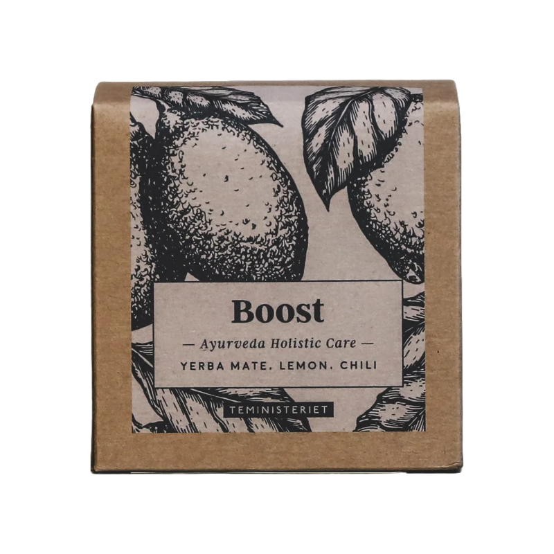 Teministeriet Ayurveda Boost te i en kvadratisk, brun papæske med et botanisk design. Forsiden har en sort-hvid illustration af citroner med blade, der omkranser en etiket med produktnavnet "Boost" i fed skrift. Under dette står "Ayurveda Holistic Care" efterfulgt af ingredienserne: yerba mate, citron og chili. Nederst ses mærket "Teministeriet". Designet har en naturlig, håndtegnet æstetik, der understøtter teens energigivende og opkvikkende tema.