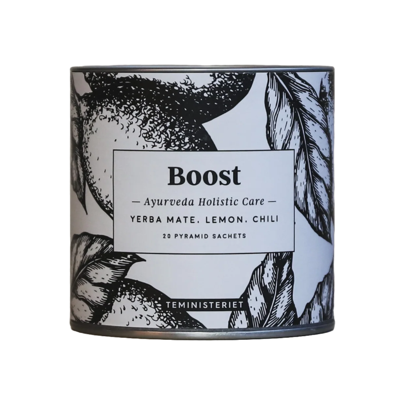 Teministeriet Ayurveda Boost te i en rund, cylinderformet metaldåse med et sort-hvidt botanisk design. Dåsen har en illustration af citroner og blade, der omkranser etiketten med produktnavnet "Boost". Under dette står "Ayurveda Holistic Care" samt ingredienserne: yerba mate, citron og chili. Derudover er det angivet, at dåsen indeholder 20 pyramide-tebreve. Designet understøtter teens friske og stimulerende egenskaber.