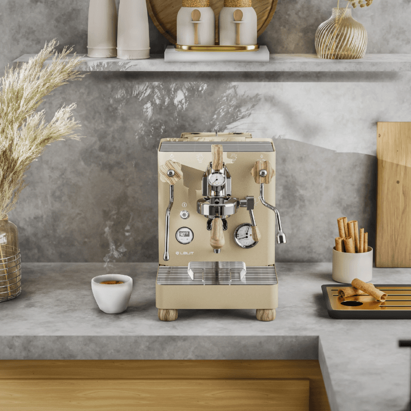Lelit Bianca espressomaskine i guldudgave med trædetaljer, placeret på en køkkenhylde med kopper og krydderier.