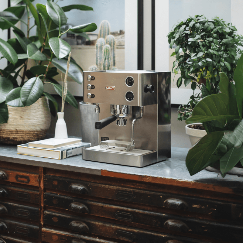 Lelit Elizabeth espressomaskine på bord omgivet af grønne planter og bøger.
