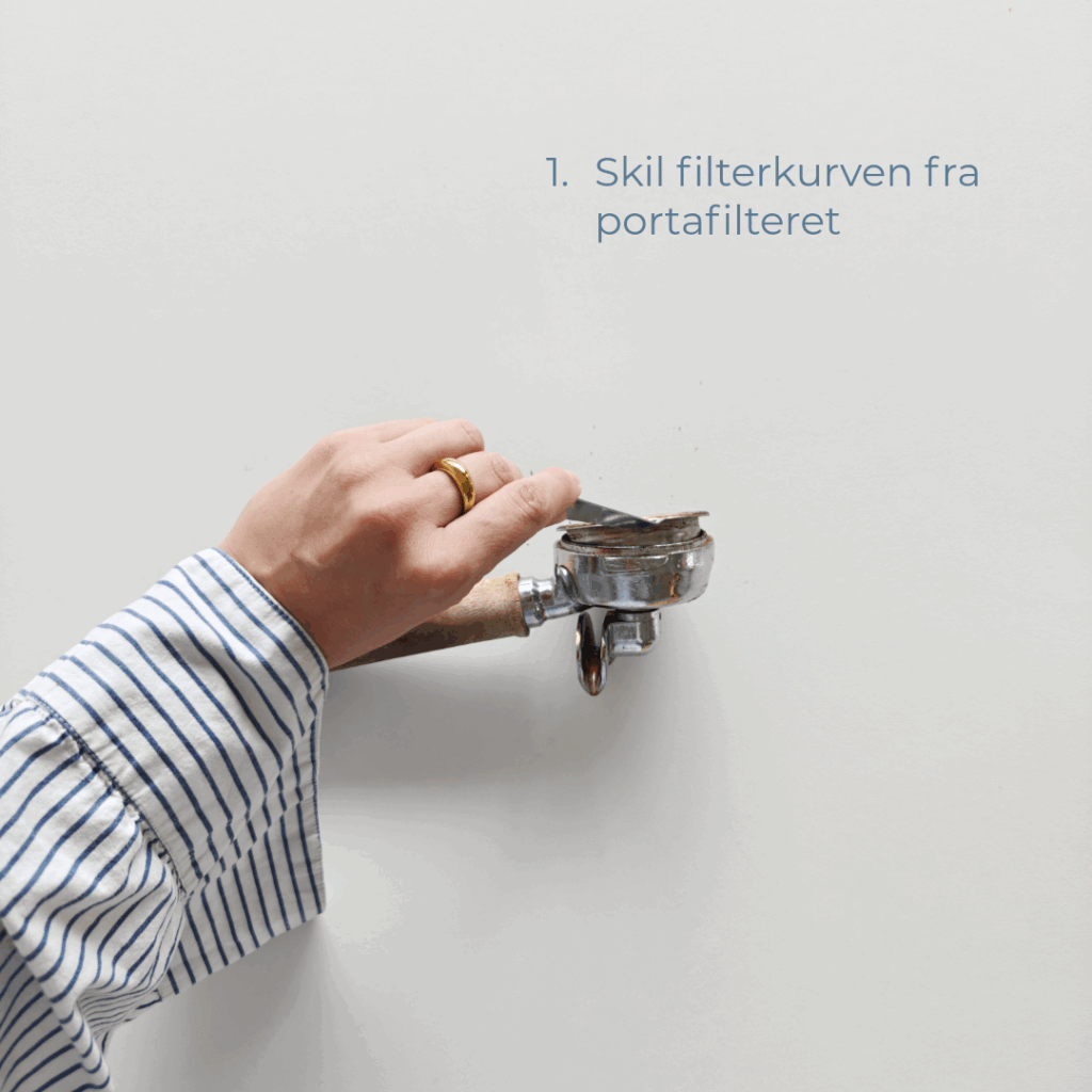Hånd med stribet skjorte bruger filterkurv-aftager til at skille filterkurven fra portafilteret.