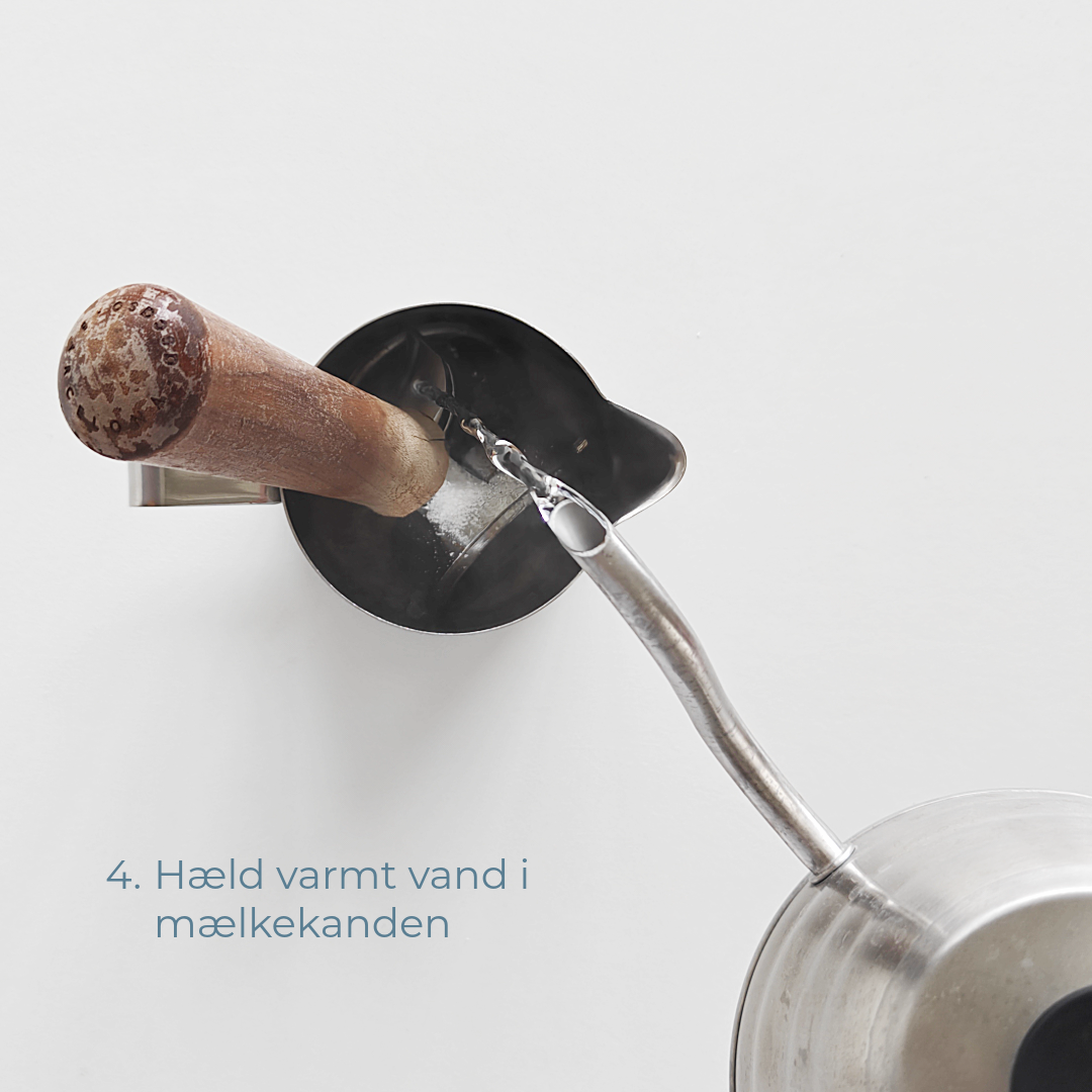 Varmt vand hældes i mælkekanden med portafilter og espressorens.