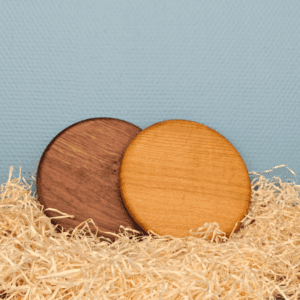 To runde låg i eg og valnød placeret i træuld mod blå baggrund.