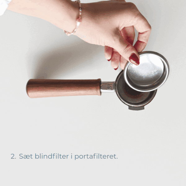 Hånd, der sætter blindfilter i portafilteret med træhåndtag.