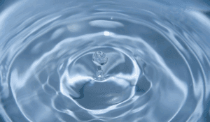 Billede af vand hvor en dråbe er ved at lande i midten a nogle vandringe