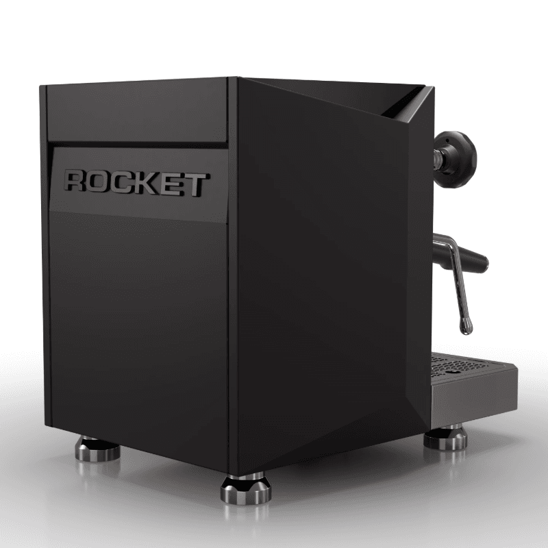 Rocket Giotto Fast V set bagfra i trekvart vinkel med indgraveret Rocket-logo på bagpanel og mat sort, vinklet sidepanel; understreger maskinens geometriske formsprog og elegante mørke finish.