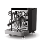 Rocket Giotto Fast R espressomaskine set i 3/4-vinkel mod fronten med portafilter monteret, synlige manometre, dampstav og refleksfri sort sidepanel med skarpe facetter; blankpoleret stålfront og ergonomisk portafilterhåndtag.