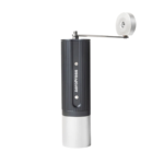 Aeropress manuel håndkværn stående på hvid baggrund, sort ribbet cylinder med sølv bund og foldbar metalarm.