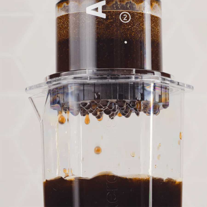 Nærbillede af kaffe, der drypper gennem AeroPress XL Clear -filterhovedet.
