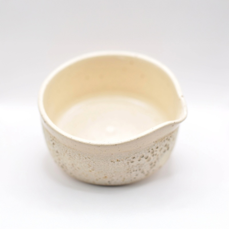Håndlavet matcha-skål set ovenfra; rund form med let uregelmæssig kant og glat indvendig glasur, beige farvetone og synlige keramikpartikler i materialet.