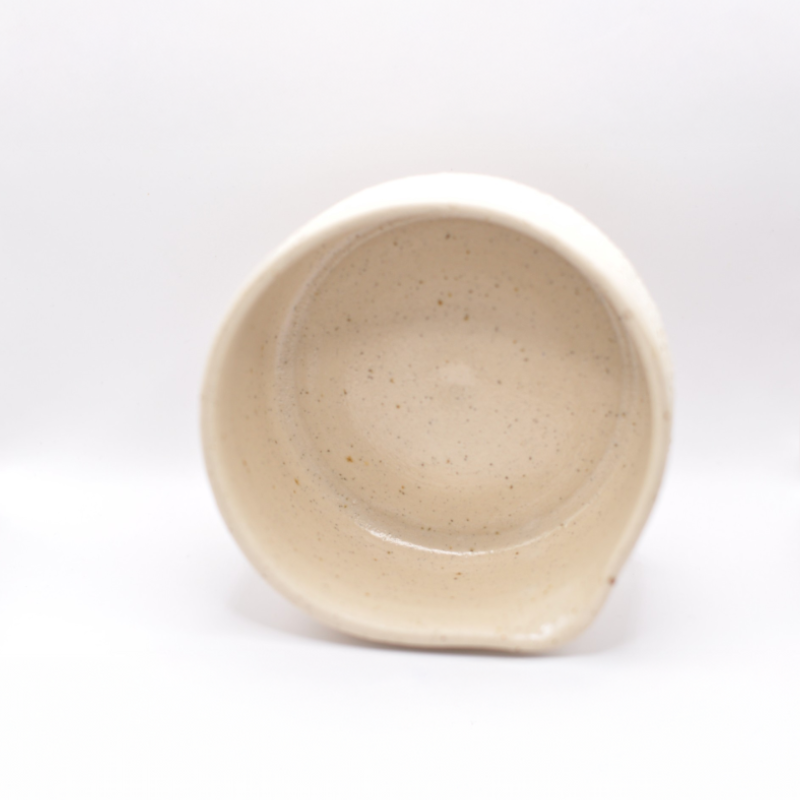 Matcha-skål set direkte ovenfra, der viser skålens glatte inderside, små naturlige prikker i leret og en diskret hældetud — minimalistisk, håndlavet keramik.